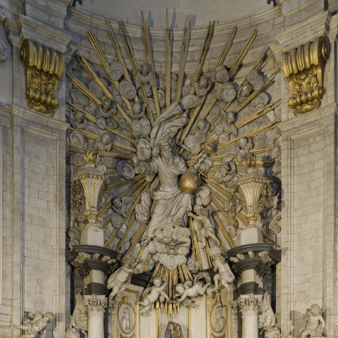 Ein prächtiger barocker Altar in einer Kirche, mit kunstvollen Skulpturen, goldenen Akzenten und strahlenden Sonnenstrahlen, der Größe und Ehrfurcht vermittelt.