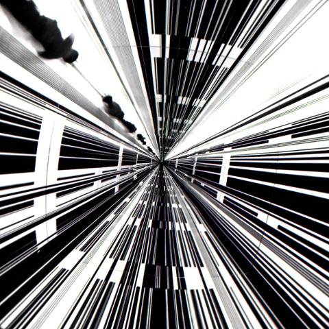 Abstract black-and-white pattern with converging lines and rectangles creates a tunnel effect, suggesting depth and movement. High contrast evokes energy.