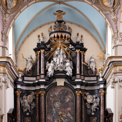 Ornate church altar with intricate sculptures and a detailed painting. The architecture features elegant curves, gold accents, and a peaceful, reverent ambiance.